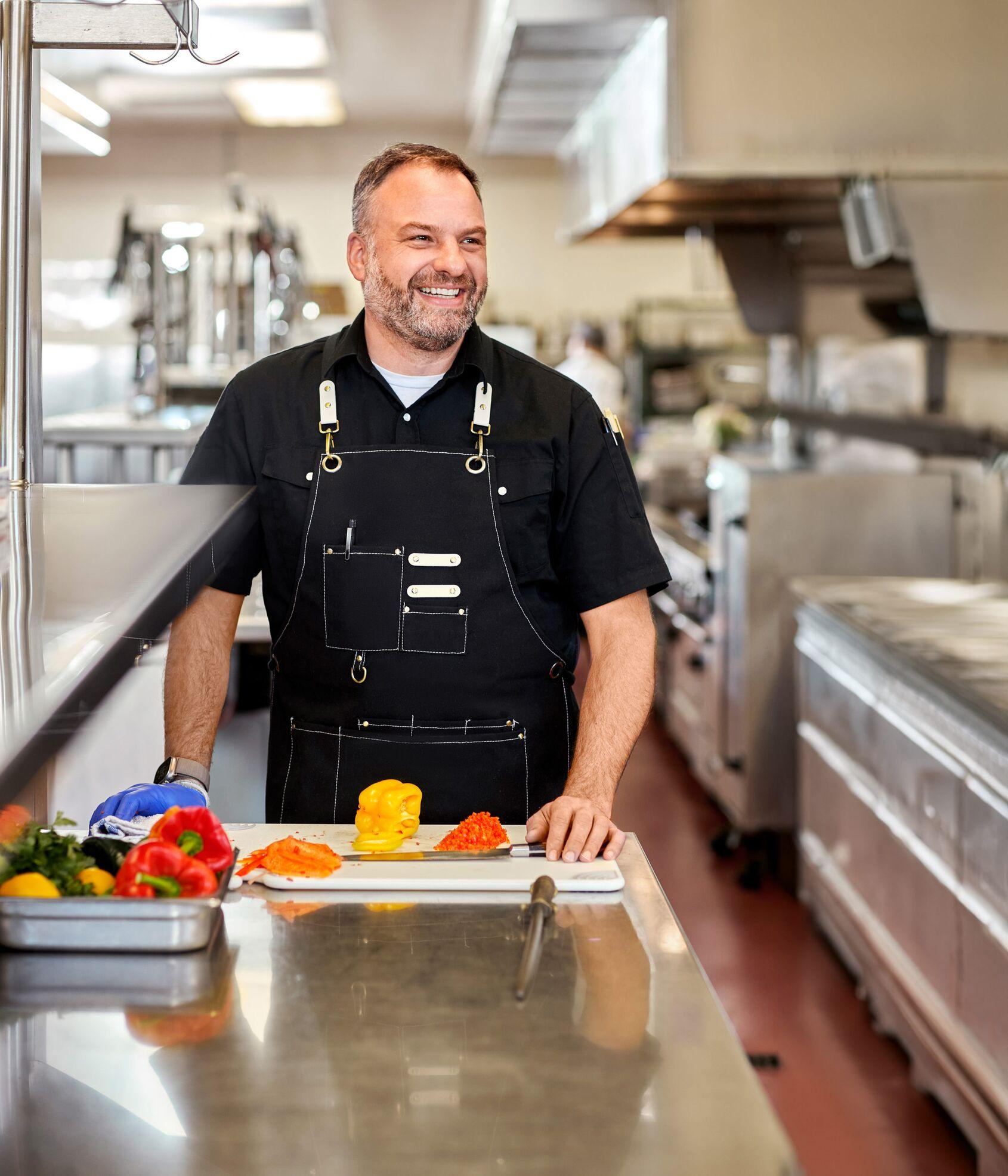 Smiling chef cutting fresh vegetables