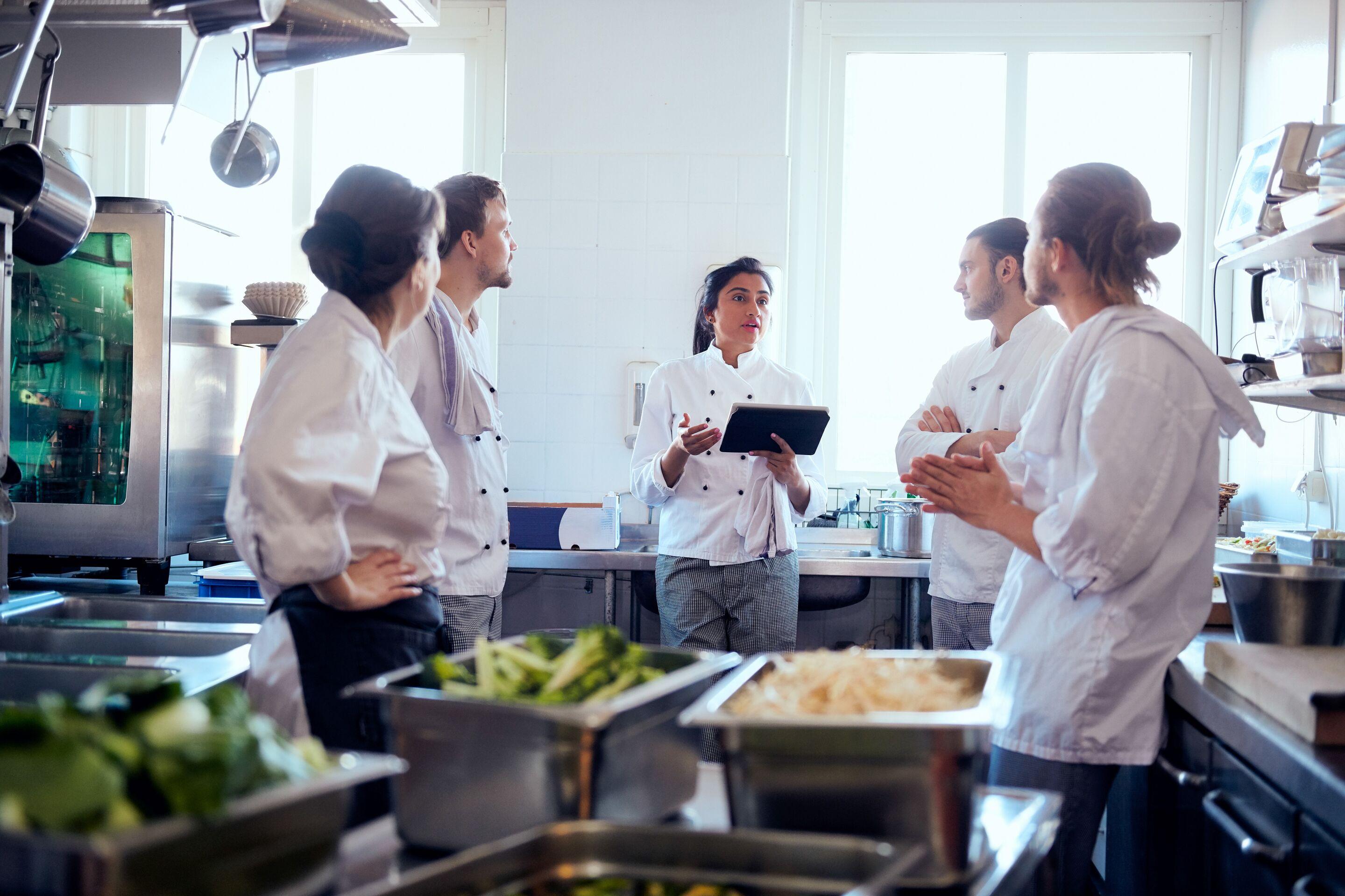 Chef holding computer tablet in a culinary team meeting