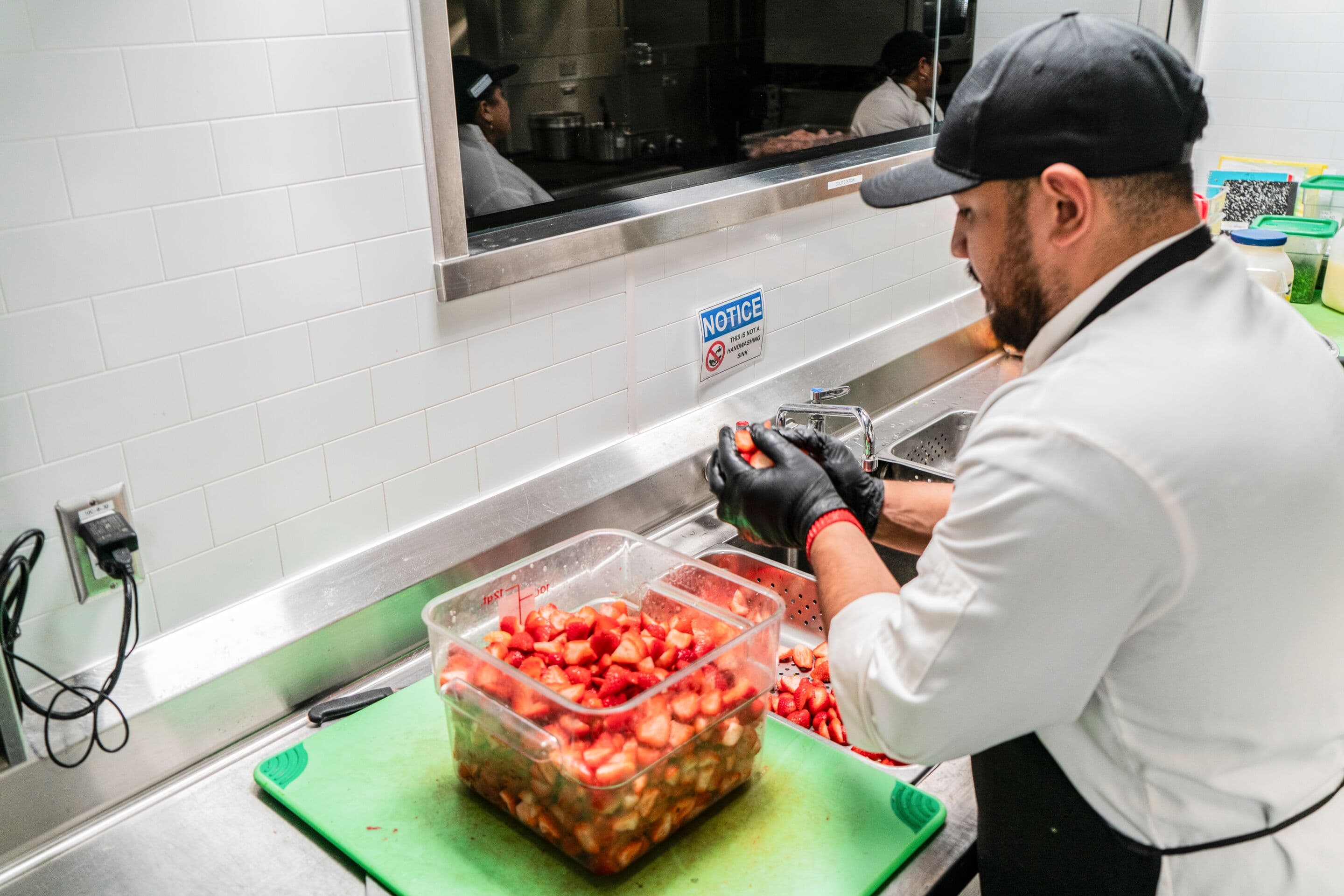 A chef carefully prepares fresh berries in a clean, organized kitchen, prioritizing food safety and a safe environment.