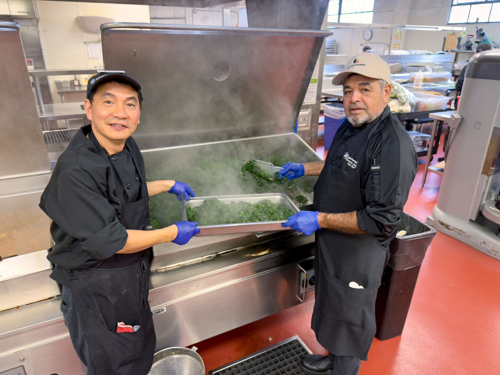Two chefs from diverse backgrounds collaborate in the kitchen, fostering a culture of belonging and teamwork through food.